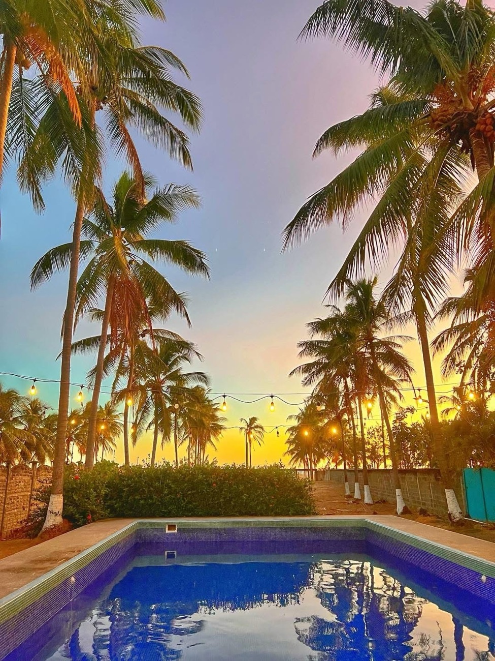 Piscina de Casa Ámbar al atardecer con luces entre las palmeras